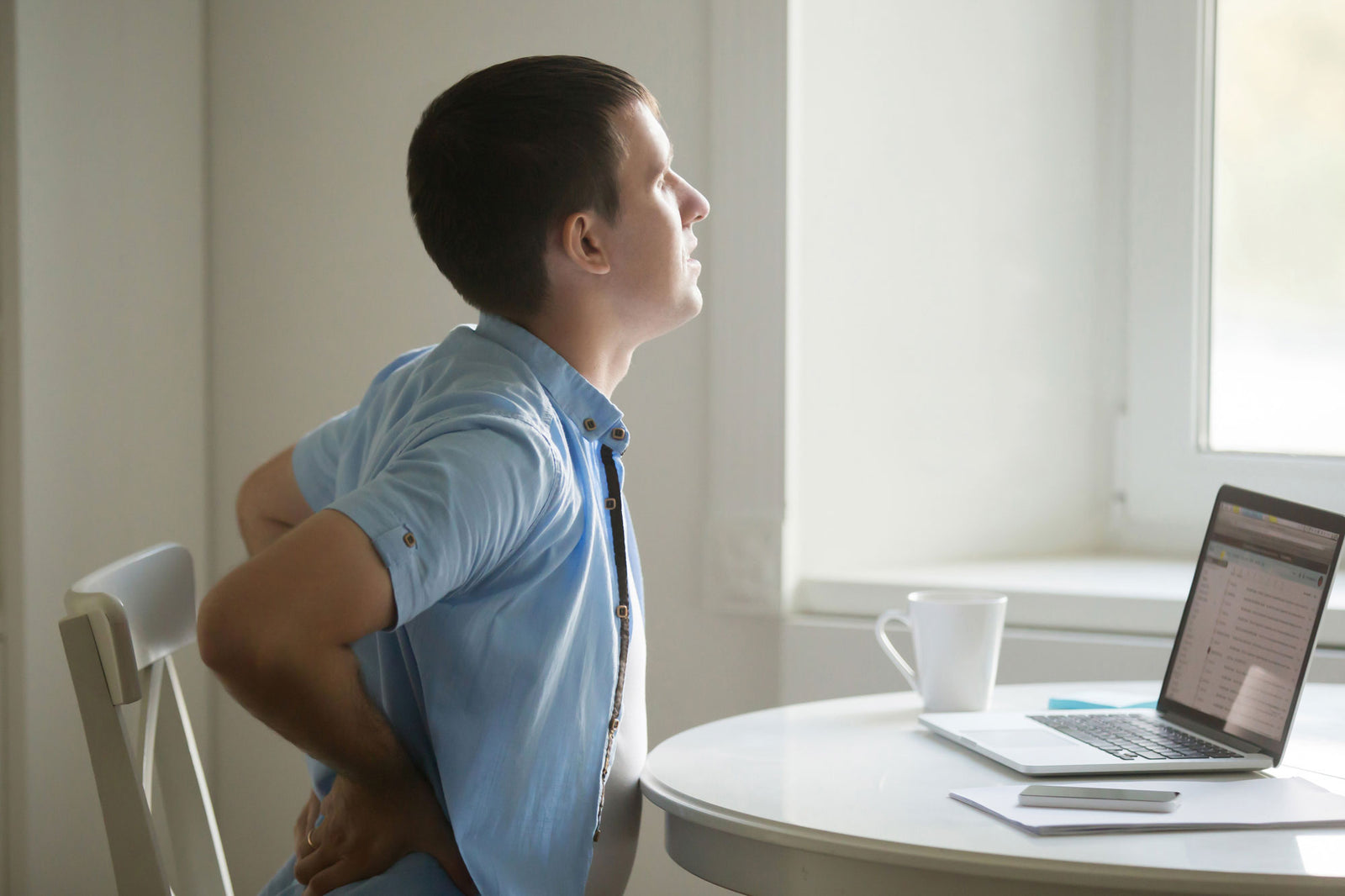 man at laptop, stretching, backache position