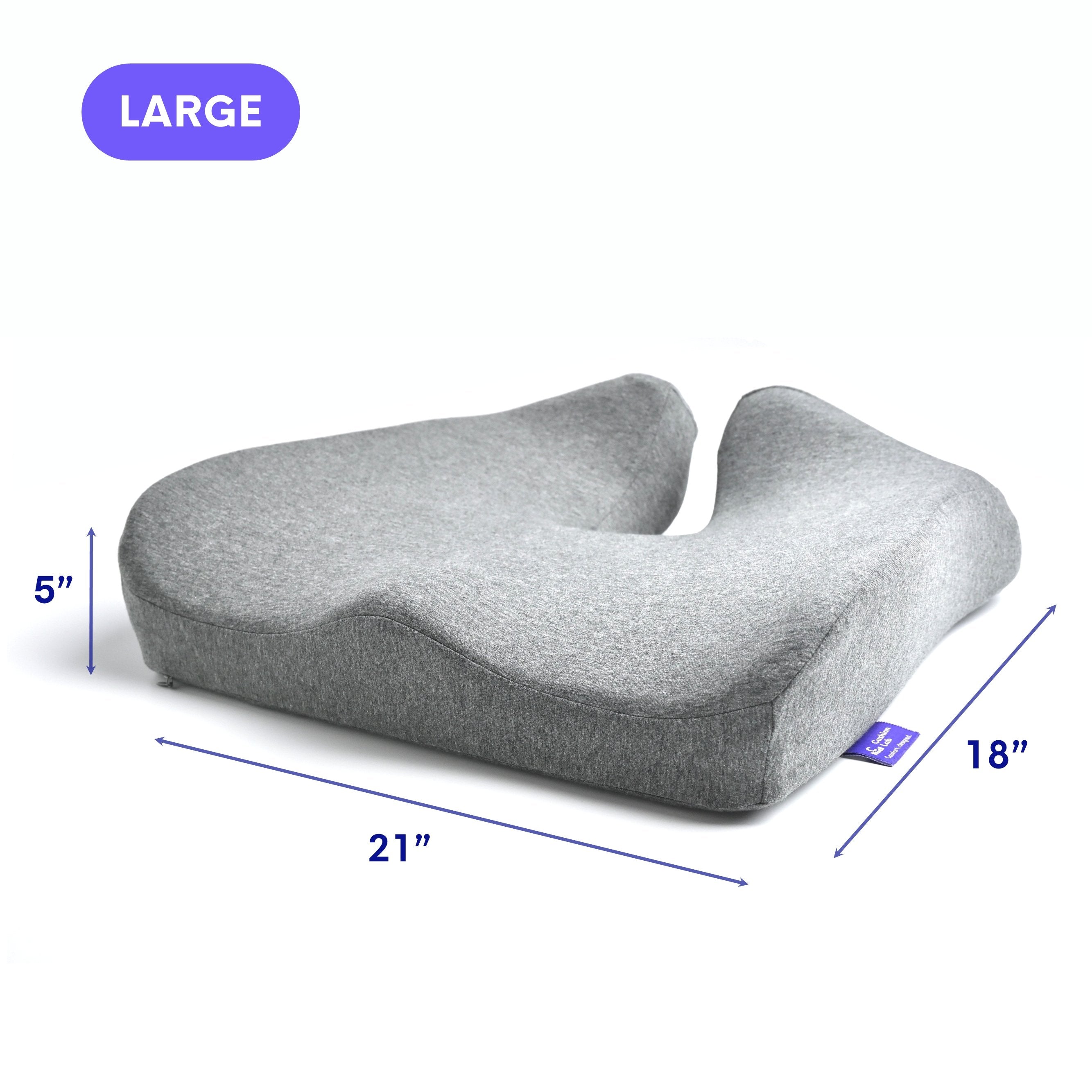 Gray ergonomic seat cushion with a central groove and contoured shape for comfort.