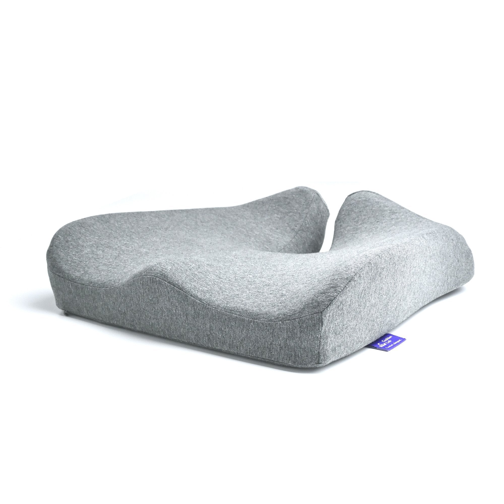 Gray ergonomic seat cushion with a central groove and contoured shape for comfort.